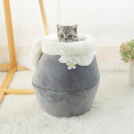 Gray pet bed with white cushion and flower decoration, featuring a cat inside.