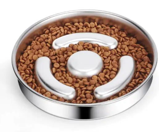 Stainless steel dog food bowl with a puzzle design filled with kibble on a white background