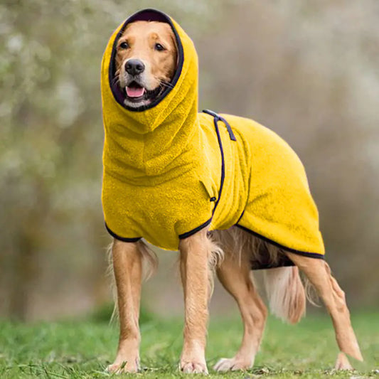 Dog wearing a yellow hooded coat outdoors on a grassy area